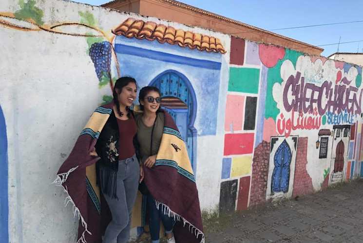 Two students standing in front of a colorful wall.