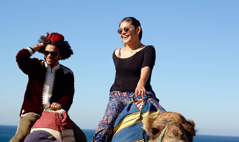 Two students riding camels.