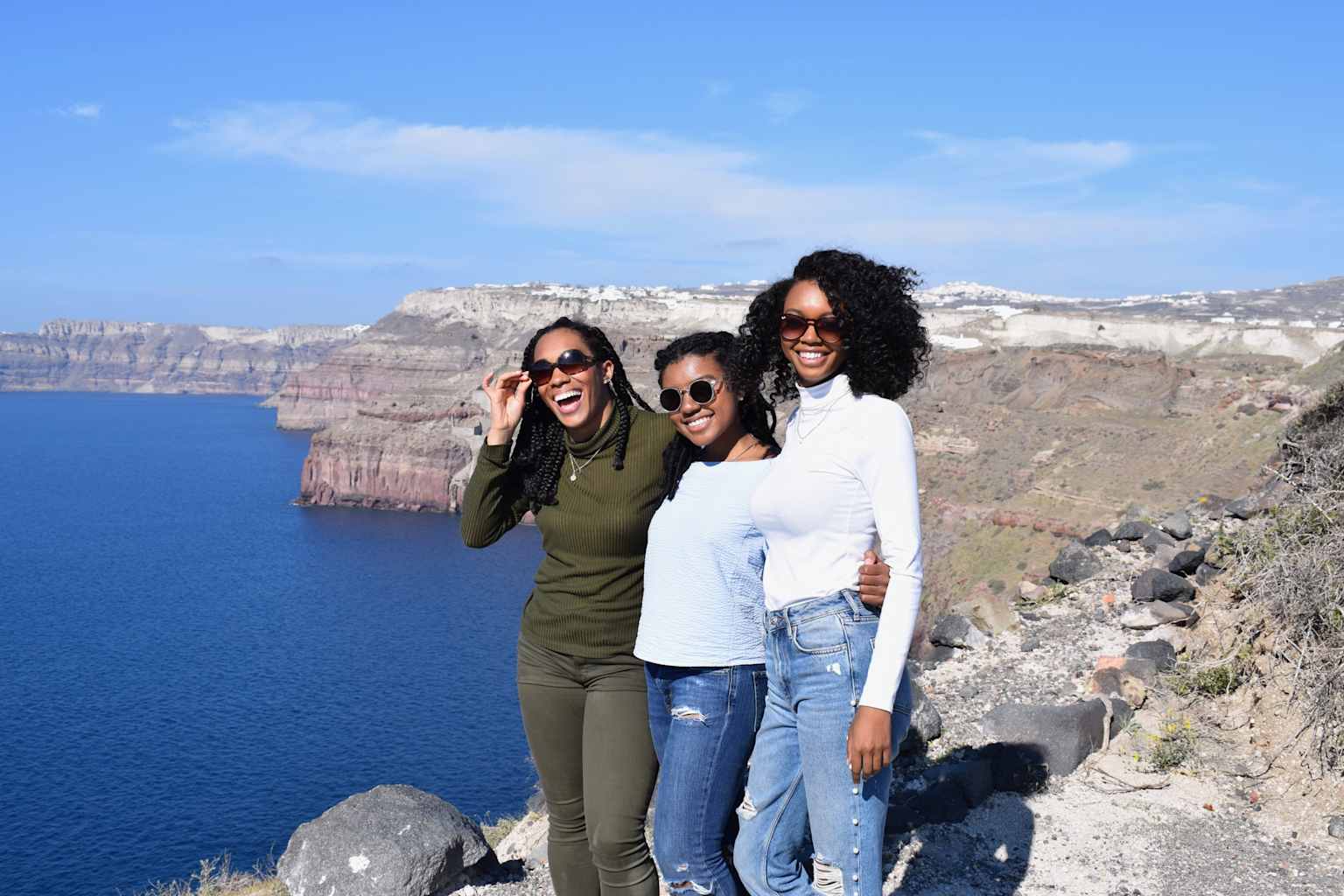 Three students smiling with a mountain view in the background.