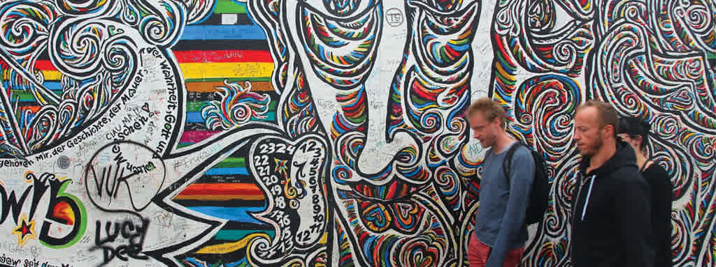 Students walk by a wall with graffiti in Berlin, Germany.