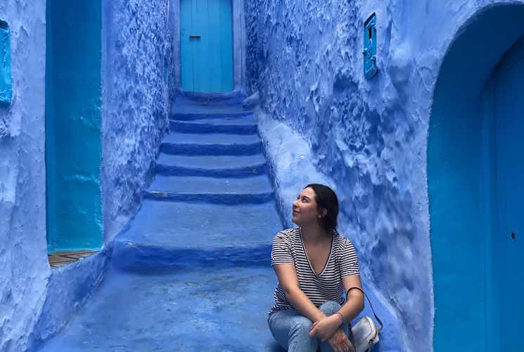 A student sitting on steps between blue buildings in Granada, Spain.