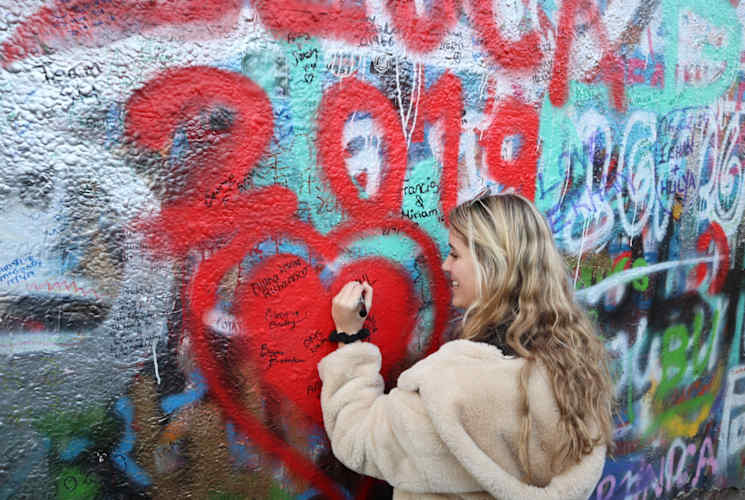 A student drawing on a wall of graffiti in Czech Republic.