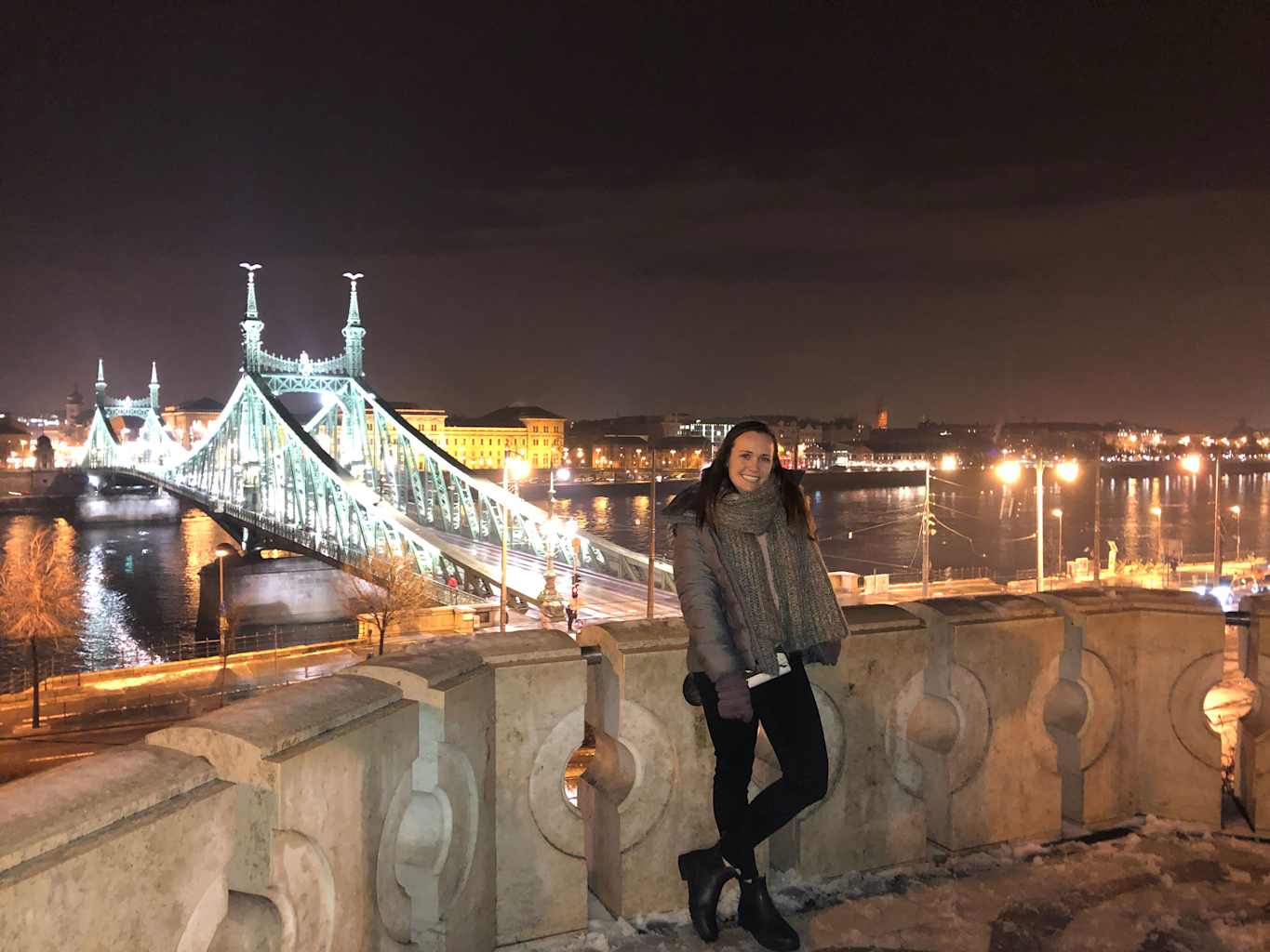 Woman in front of a bridge at night.