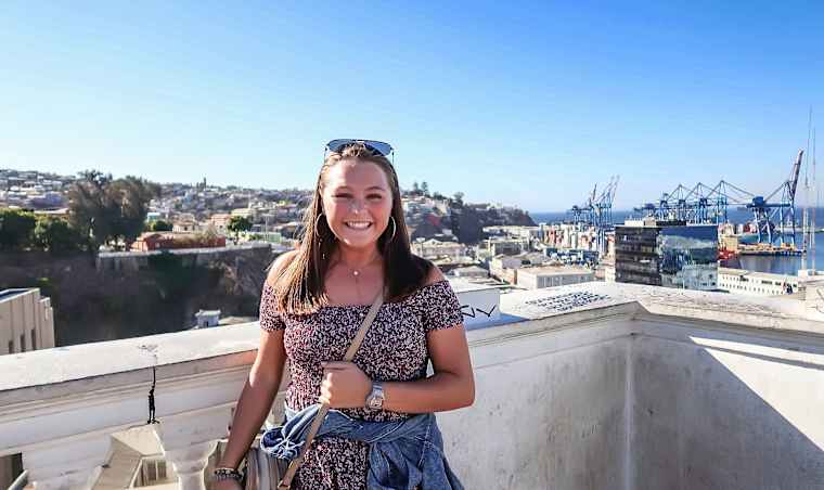 A student on the roof of a building overlooking a city.