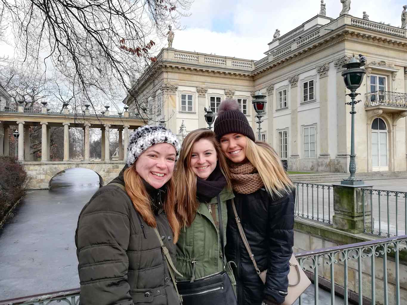 Three girls smiling in front of building.