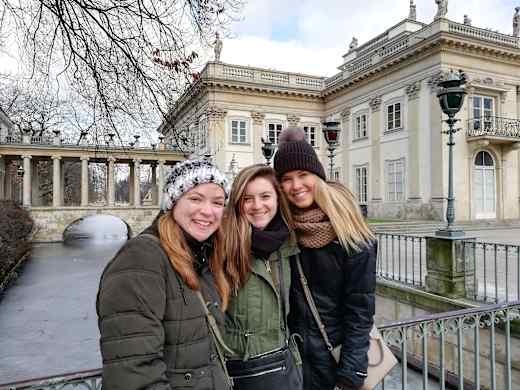 Three girls smiling in front of building.