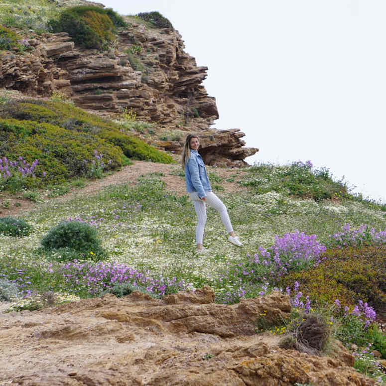 A student walking through a field with purple flowers.