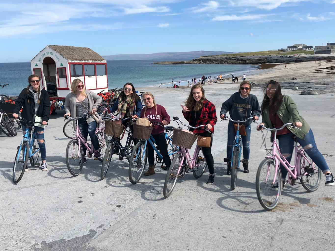 Girls posing on bikes in front of beach.