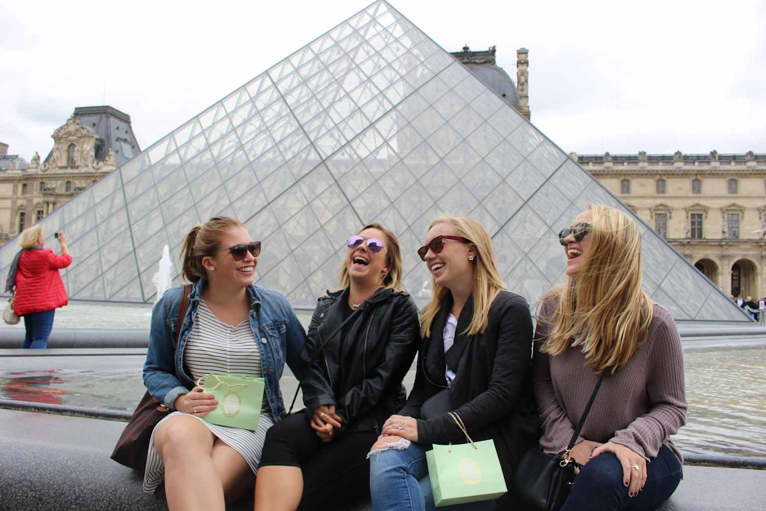 Four students sitting outside the Louvre.