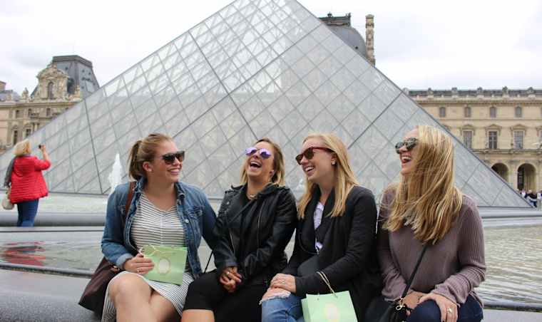 Four students sitting outside the Louvre.