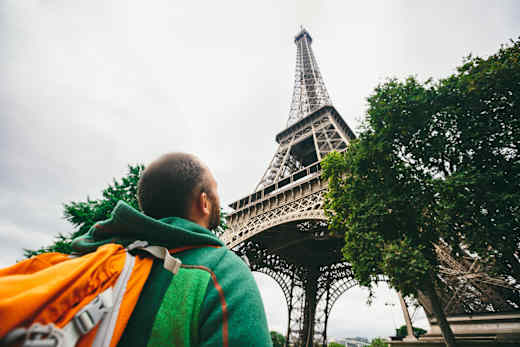 Student gazes up at Eiffel Tower in Paris, France.