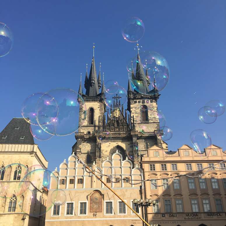 Bubbles floating in front of a building in Prague.