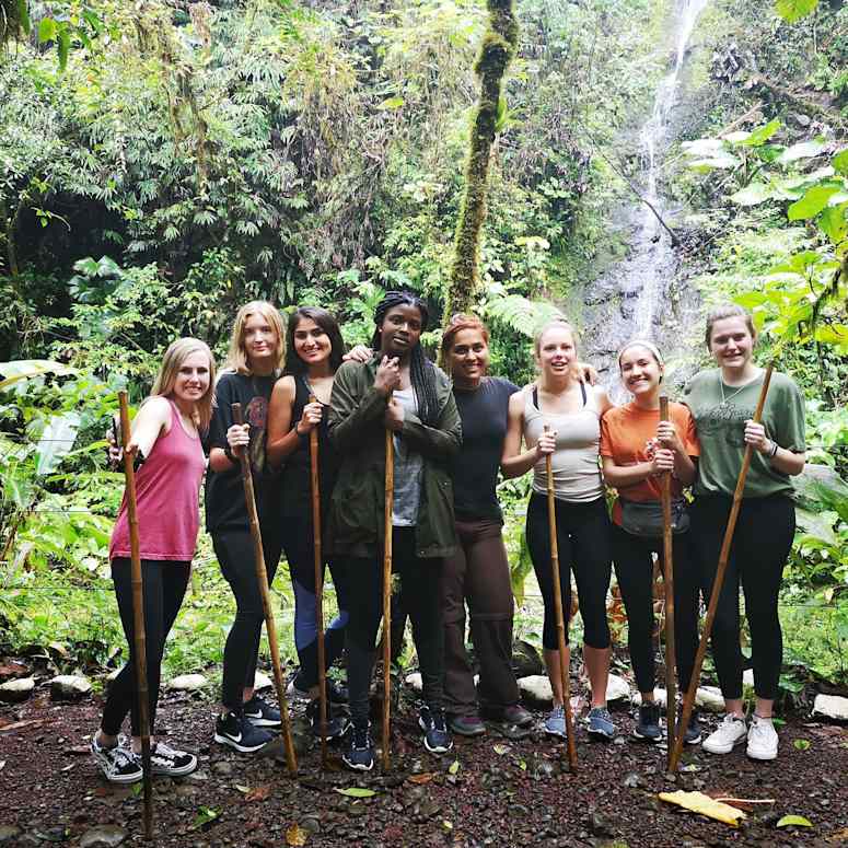 Hiking group posing next to waterfall.