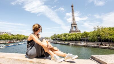 Young woman sitting in front of Eiffel Tower in Paris, France during summer